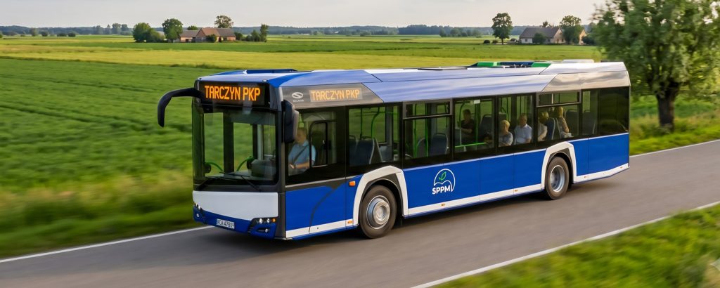 Niebieski autobus z logiem SPPM jadący pozamiejską drogą.